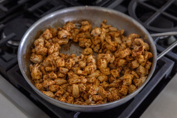 Chicken breast in a pan with taco seasoning.