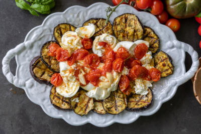 Eggplant, burrata and roasted tomatoes on a plate.