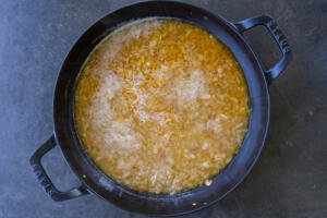 Broth added to orzo in a pan.
