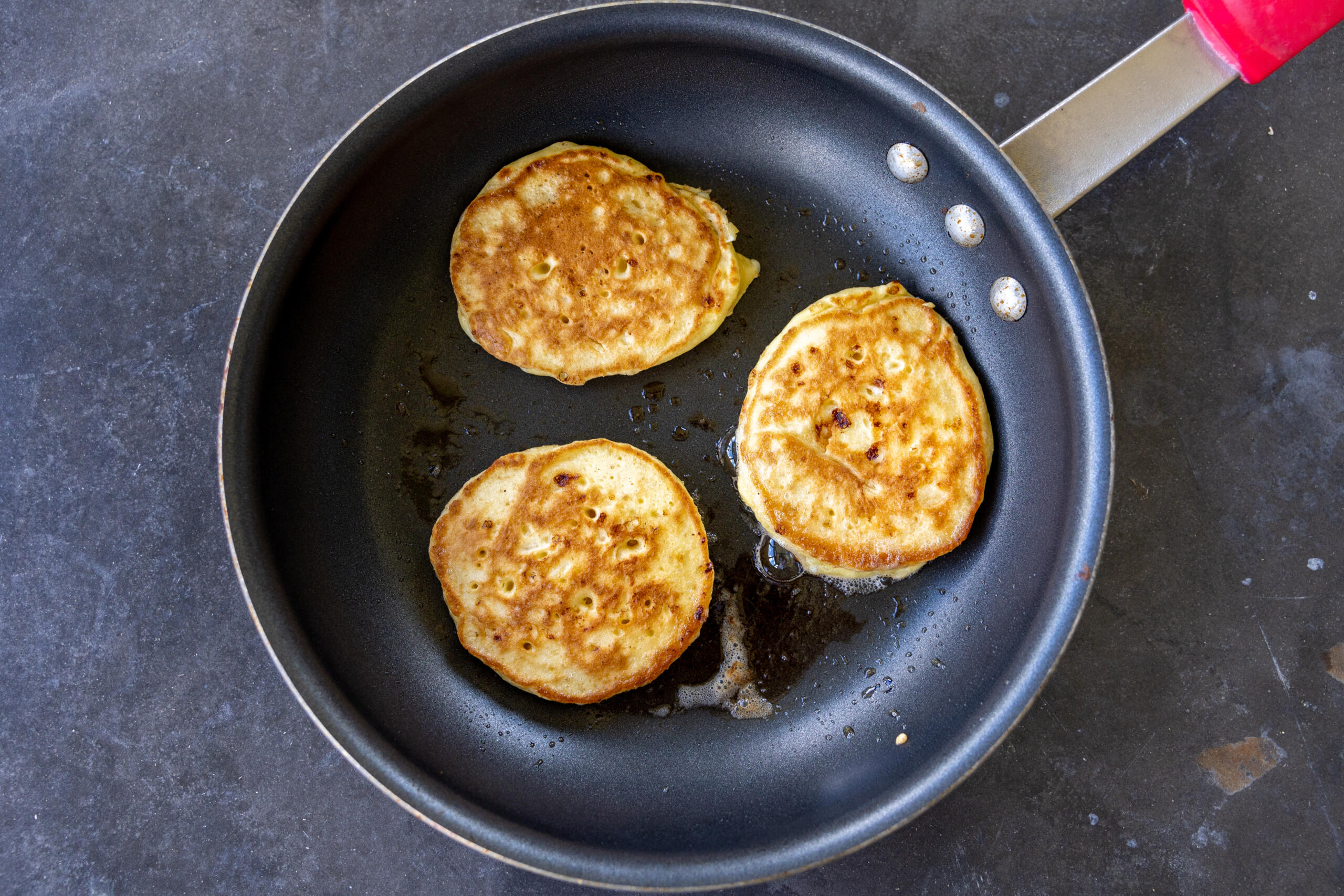 Sourdough Cottage Cheese Pancakes browing on a pan.